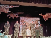6 osób w strojach żołnierskich stoi na scenie.
