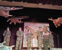 6 osób w strojach żołnierskich stoi na scenie.