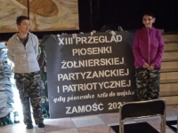 dwie kobiet pozują przy banerze informacyjnym XII Przegląd Piosenki Żołnierskiej, Partyzanckiej i Patriotycznej