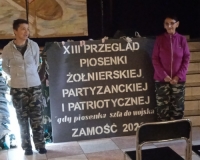 dwie kobiet pozują przy banerze informacyjnym XII Przegląd Piosenki Żołnierskiej, Partyzanckiej i Patriotycznej